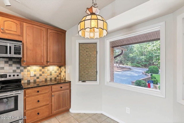120 Shagbark Ct, Seven Lakes, NC 27376 - kitchen featuring appliances with stainless steel finishes, tasteful backsplash, light tile patterned floors, dark stone counters, and lofted ceiling