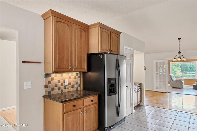 120 Shagbark Ct, Seven Lakes, NC 27376 - kitchen with stainless steel fridge with ice dispenser, backsplash, light tile patterned floors, dark stone countertops, and a chandelier