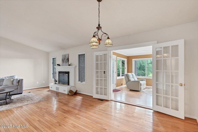 120 Shagbark Ct, Seven Lakes, NC 27376 - living area with hardwood / wood-style flooring, a brick fireplace, french doors, a chandelier, and lofted ceiling