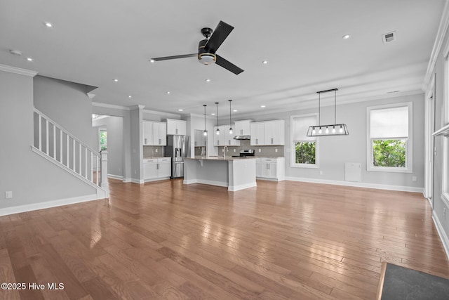 1035 Bent Blade Ln, Wilmington, NC 28411 - unfurnished living room with ceiling fan, crown molding, recessed lighting, light wood finished floors, and stairs
