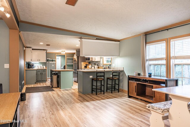 1360 Rays Bridge Rd, Whispering Pines, NC 28327 - kitchen featuring a textured ceiling, ornamental molding, a kitchen bar, a peninsula, and light wood finished floors