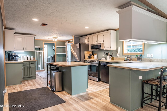 1360 Rays Bridge Rd, Whispering Pines, NC 28327 - kitchen featuring appliances with stainless steel finishes, a textured ceiling, a breakfast bar, a peninsula, and white cabinetry