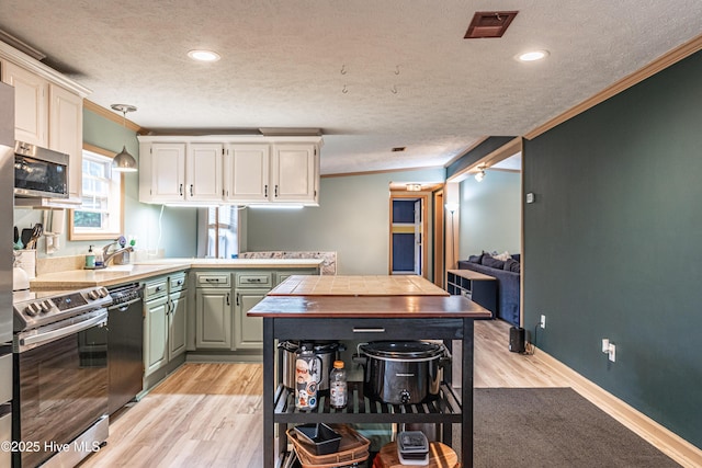 1360 Rays Bridge Rd, Whispering Pines, NC 28327 - kitchen with stainless steel appliances, crown molding, a textured ceiling, light wood-style floors, and a peninsula