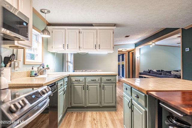 1360 Rays Bridge Rd, Whispering Pines, NC 28327 - kitchen with appliances with stainless steel finishes, crown molding, green cabinets, a textured ceiling, and light wood-style floors