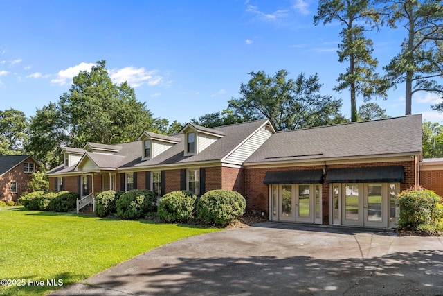 1909 Pawnee Dr, Kinston, NC 28504 - view of front facade featuring brick siding, french doors, a front yard, driveway, and a shingled roof