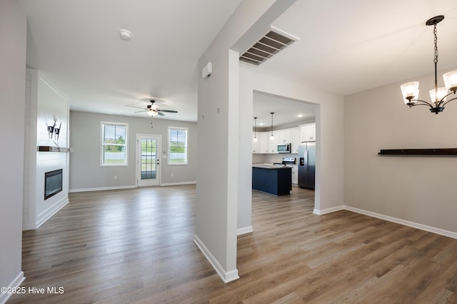 6001 Farmwood Loop, Wilson, NC 27896 - unfurnished living room featuring a ceiling fan, wood finished floors, a fireplace, and a chandelier