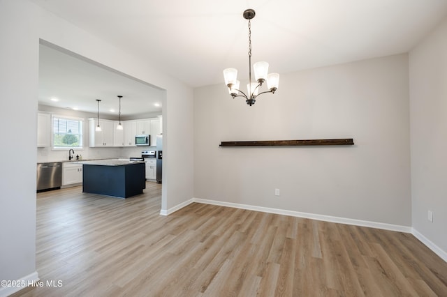 6001 Farmwood Loop, Wilson, NC 27896 - kitchen with stainless steel appliances, light wood-type flooring, white cabinetry, light countertops, and a chandelier
