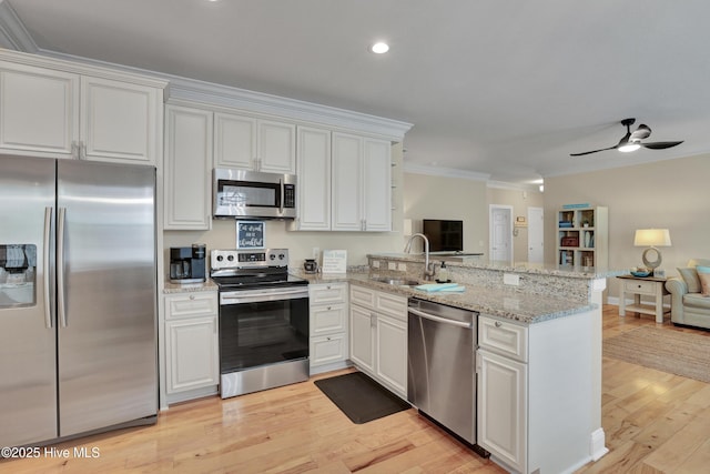 215 NE 54th St, Oak Island, NC 28465 - kitchen featuring stainless steel appliances, open floor plan, a peninsula, ornamental molding, and white cabinets