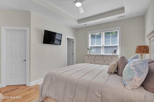 215 NE 54th St, Oak Island, NC 28465 - bedroom featuring light wood-style flooring, a ceiling fan, and a tray ceiling
