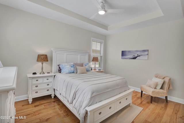 215 NE 54th St, Oak Island, NC 28465 - bedroom featuring light wood finished floors, a tray ceiling, and a ceiling fan