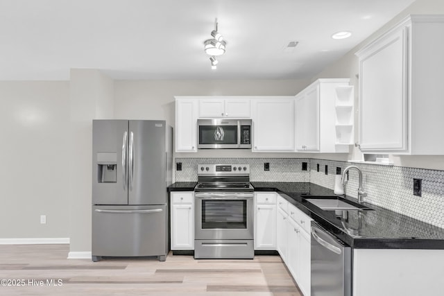 1004 S 8th St, Wilmington, NC 28401 - kitchen with stainless steel appliances, dark countertops, white cabinets, decorative backsplash, and light wood-style flooring