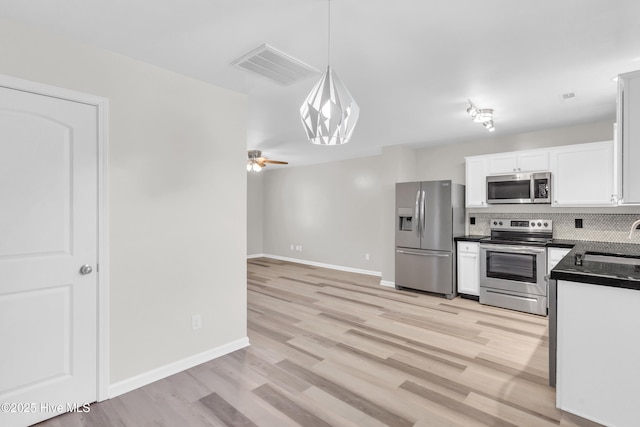 1004 S 8th St, Wilmington, NC 28401 - kitchen featuring appliances with stainless steel finishes, dark countertops, backsplash, white cabinetry, and hanging light fixtures