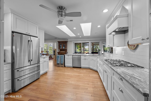110 Mariners Ct, New Bern, NC 28562 - kitchen featuring appliances with stainless steel finishes, a skylight, ceiling fan, beverage cooler, and white cabinetry
