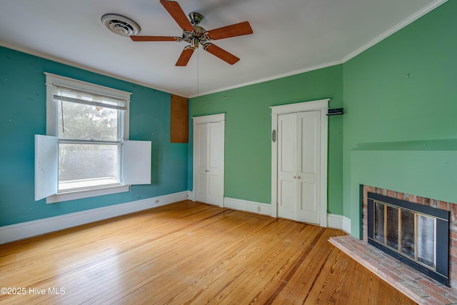 1305 N Market St, Washington, NC 27889 - unfurnished bedroom featuring multiple closets, hardwood / wood-style floors, a brick fireplace, crown molding, and a ceiling fan