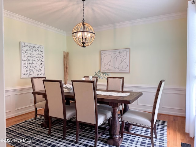 4109 Devonshire Ln, Wilmington, NC 28409 - dining space with a chandelier, wood finished floors, crown molding, and a wainscoted wall