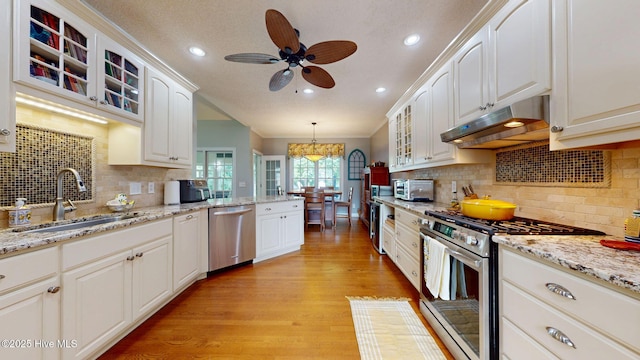 104 Chatham Pass, Trent Woods, NC 28562 - kitchen with stainless steel appliances, under cabinet range hood, light wood-style flooring, ceiling fan, and glass insert cabinets