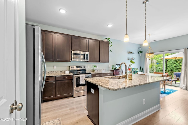 1571 Grey Cliff Run, Wilmington, NC 28405 - kitchen with stainless steel appliances, light wood-type flooring, dark brown cabinets, hanging light fixtures, and an island with sink