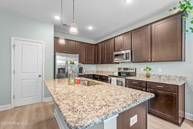 1571 Grey Cliff Run, Wilmington, NC 28405 - kitchen featuring appliances with stainless steel finishes, dark brown cabinetry, light wood finished floors, decorative light fixtures, and recessed lighting