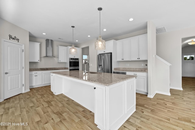 132 Mill Run, South Mills, NC 27976 - kitchen with stainless steel fridge, wall chimney exhaust hood, light wood-type flooring, white cabinets, and an island with sink