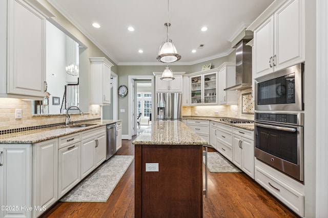 8812 Fazio Dr, Wilmington, NC 28411 - kitchen with appliances with stainless steel finishes, wall chimney range hood, a kitchen island, white cabinetry, and ornamental molding
