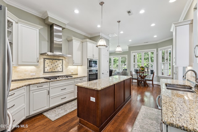 8812 Fazio Dr, Wilmington, NC 28411 - kitchen featuring wall chimney range hood, stainless steel appliances, a center island, recessed lighting, and white cabinets