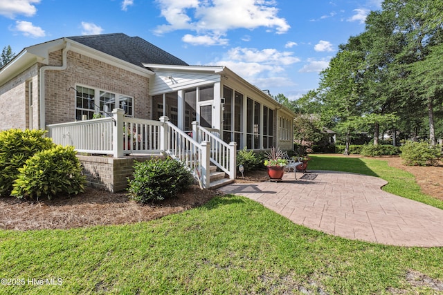 8812 Fazio Dr, Wilmington, NC 28411 - rear view of house with a sunroom, a patio area, brick siding, and a lawn