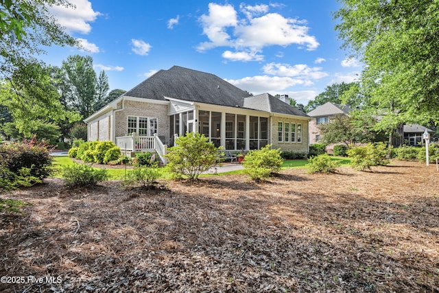 8812 Fazio Dr, Wilmington, NC 28411 - rear view of house featuring a sunroom, brick siding, and a chimney