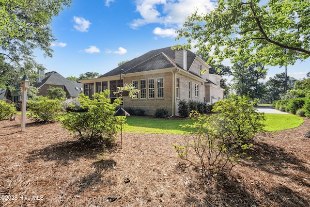 8812 Fazio Dr, Wilmington, NC 28411 - back of house featuring brick siding, a lawn, a chimney, and a shingled roof