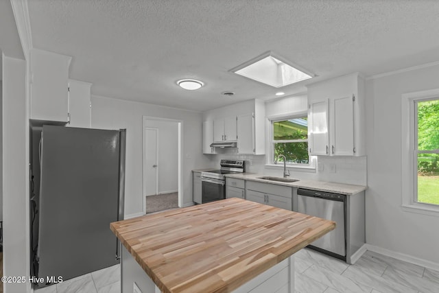 1292 Lake Cole Rd, Midway Park, NC 28544 - kitchen featuring stainless steel appliances, a skylight, butcher block countertops, light marble finish floors, and white cabinets