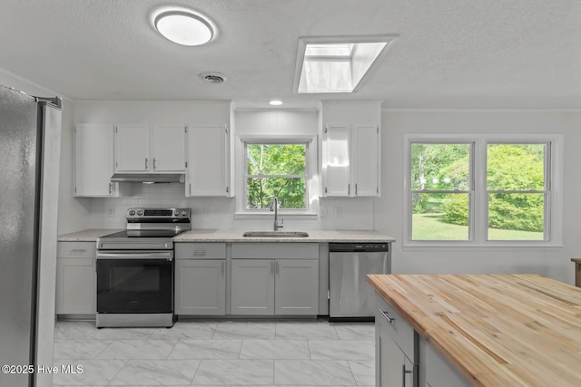 1292 Lake Cole Rd, Midway Park, NC 28544 - kitchen featuring stainless steel appliances, under cabinet range hood, light marble finish floors, butcher block counters, and backsplash