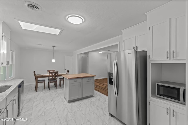 1292 Lake Cole Rd, Midway Park, NC 28544 - kitchen featuring appliances with stainless steel finishes, butcher block counters, light marble finish flooring, decorative light fixtures, and a skylight