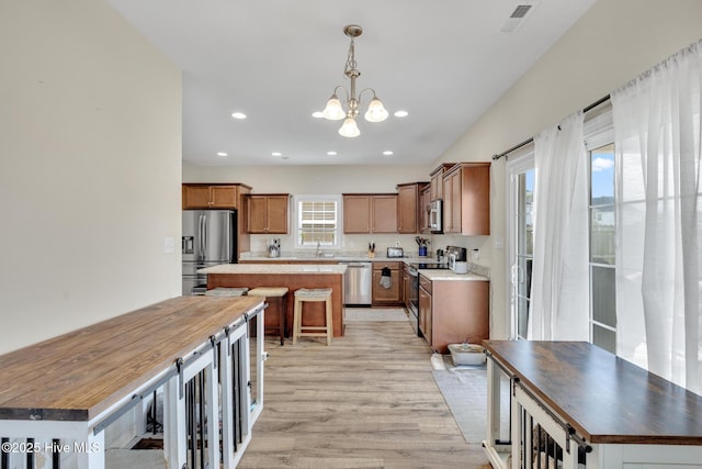 324 Windmill Light Way, Sneads Ferry, NC 28460 - kitchen featuring appliances with stainless steel finishes, a kitchen island, light wood-type flooring, a chandelier, and a kitchen breakfast bar