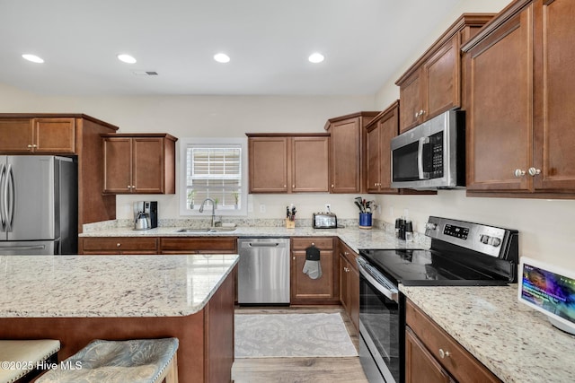 324 Windmill Light Way, Sneads Ferry, NC 28460 - kitchen featuring appliances with stainless steel finishes, light stone countertops, light wood-style floors, a breakfast bar area, and recessed lighting
