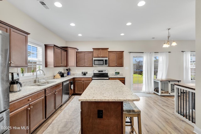 324 Windmill Light Way, Sneads Ferry, NC 28460 - kitchen featuring appliances with stainless steel finishes, a breakfast bar, a kitchen island, light wood-style flooring, and light stone countertops