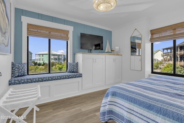 8801 Reed Dr Unit 116West, Emerald Isle, NC 28594 - bedroom featuring crown molding, a decorative wall, multiple windows, and light wood-style flooring