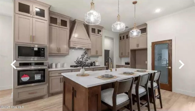 209 Planters Ridge Dr, Sunset Beach, NC 28468 - kitchen featuring stainless steel appliances, custom range hood, a center island with sink, light countertops, and hanging light fixtures