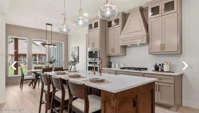 209 Planters Ridge Dr, Sunset Beach, NC 28468 - kitchen featuring custom exhaust hood, appliances with stainless steel finishes, an island with sink, light countertops, and decorative light fixtures