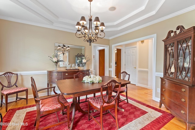 2710 Scarborough Way, Southport, NC 28461 - dining space with a chandelier, a tray ceiling, wood finished floors, and ornamental molding