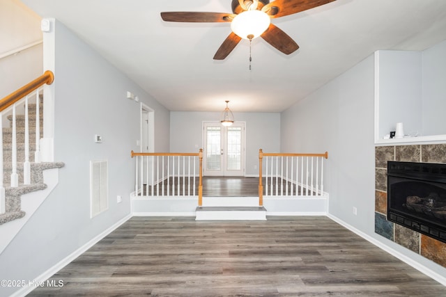 115 Billets Bridge Rd, Camden, NC 27921 - unfurnished living room with wood finished floors, french doors, ceiling fan, stairway, and a tiled fireplace