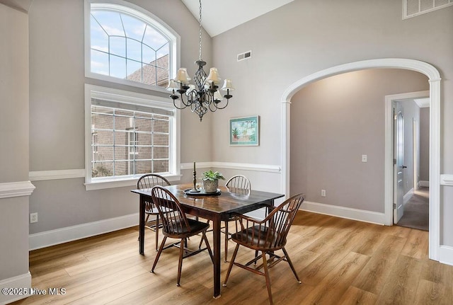 428 Windchime Dr, Wilmington, NC 28412 - dining space with arched walkways, light wood-style flooring, a chandelier, plenty of natural light, and high vaulted ceiling