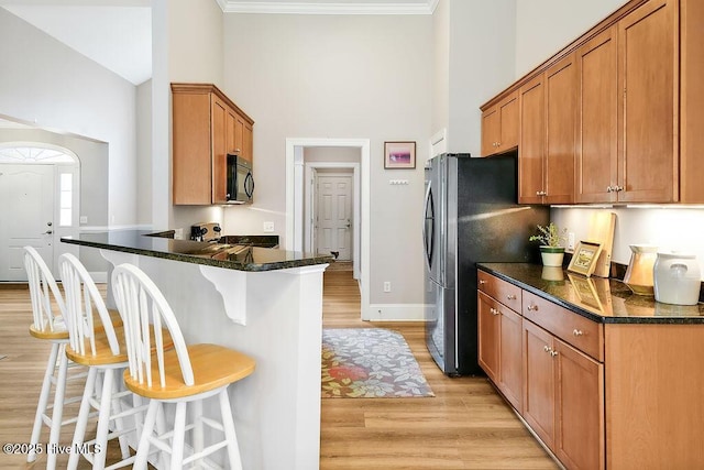 428 Windchime Dr, Wilmington, NC 28412 - kitchen featuring a high ceiling, black microwave, a breakfast bar, light wood-style flooring, and stove