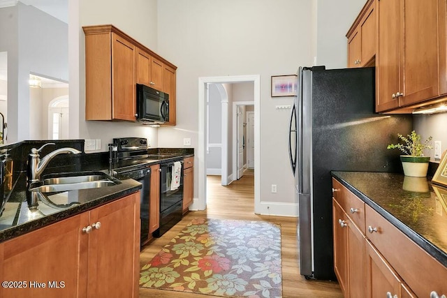 428 Windchime Dr, Wilmington, NC 28412 - kitchen featuring black appliances, a high ceiling, light wood-style flooring, brown cabinets, and dark stone counters