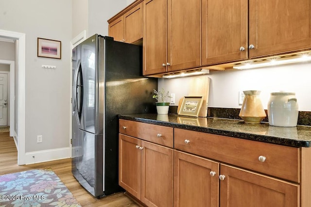 428 Windchime Dr, Wilmington, NC 28412 - kitchen with freestanding refrigerator, light wood-style flooring, brown cabinetry, and dark stone counters