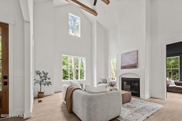 575 E Morganton Rd, Southern Pines, NC 28387 - living area featuring high vaulted ceiling, a glass covered fireplace, healthy amount of natural light, light wood-style flooring, and beamed ceiling