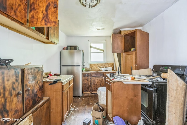 115 Wright St, Wilmington, NC 28401 - kitchen featuring freestanding refrigerator, dark wood-style flooring, brown cabinetry, and light countertops
