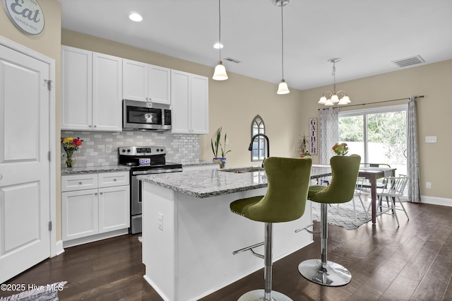 121 Poplar Branch Way, Hampstead, NC 28443 - kitchen with appliances with stainless steel finishes, dark wood-style flooring, a breakfast bar area, white cabinetry, and recessed lighting