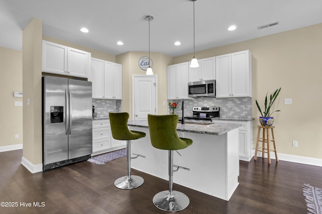 121 Poplar Branch Way, Hampstead, NC 28443 - kitchen featuring appliances with stainless steel finishes, dark wood-type flooring, light stone countertops, tasteful backsplash, and an island with sink