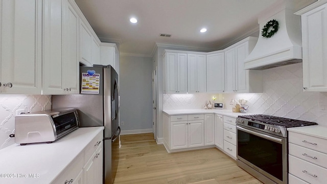 812 Vineyard Dr, New Bern, NC 28562 - kitchen with stainless steel gas range oven, wall chimney exhaust hood, crown molding, light wood-type flooring, and white cabinets