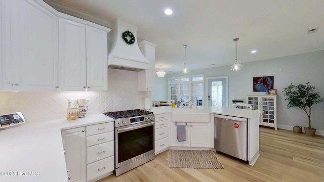 812 Vineyard Dr, New Bern, NC 28562 - kitchen with appliances with stainless steel finishes, wall chimney exhaust hood, a peninsula, light wood-style floors, and backsplash