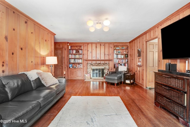 1714 E Walnut St, Goldsboro, NC 27530 - living room featuring wood walls, built in shelves, wood finished floors, a fireplace, and crown molding